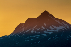 Midnight sun behind a mountain peak, Djupivogur